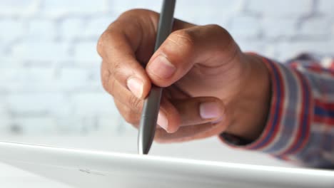 close-up of a person's hand using a stylus on a tablet