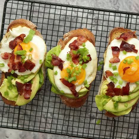 Tasty-delicious-homemade-toasts-with-fried-egg--bacon--avocado--lettuce-and-chive--Served-on-grill