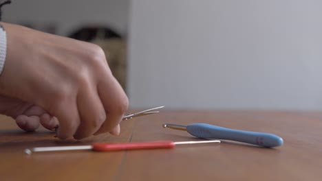 crotchet or knitting tools needles, hooks, and flat sewing scissors placed on table