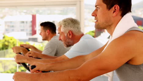 Three-men-working-out-on-exercise-bikes