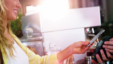 mujer pagando facturas a través de un teléfono inteligente utilizando tecnología nfc