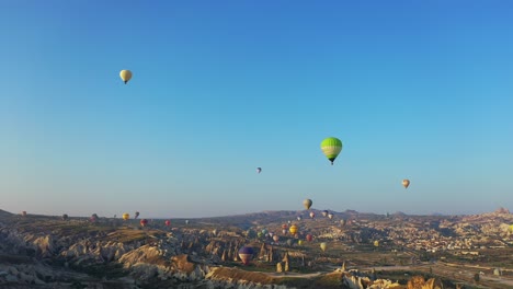 globos aerostáticos flotando sobre el paisaje de capadocia al amanecer, panorámica aérea a la izquierda