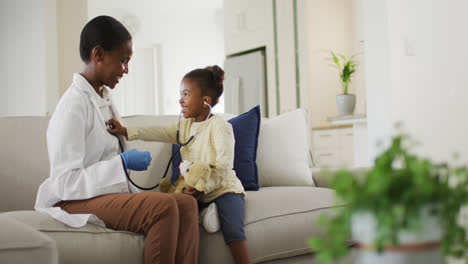 African-american-girl-using-stethoscope-and-smiling-during-medical-home-visit