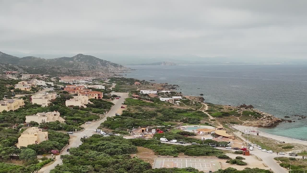Vista costiera della Sardegna con case e mare sotto un cielo nuvoloso