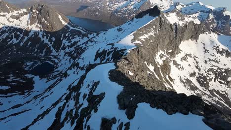 FPV-Aufnahmen-Einer-Drohne,-Die-Während-Der-Mitternachtssonne-In-Nordnorwegen-Entlang-Schneebedeckter-Bergkämme-über-Den-Fjorden-Abtaucht