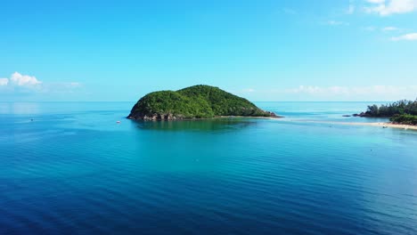 small rocky island with green tropical lush vegetation surrounded by calm blue azure lagoon under bright sky in vietnam