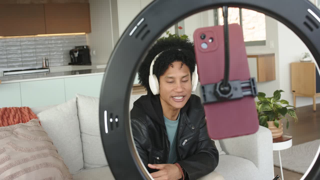 Dopo essersi sistemato, uomo che indica, parla ed enfatizza i punti sullo smartphone con ring light a casa