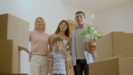 familia emocionada de pie en un nuevo apartamento lleno de cajas de cartón