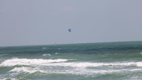 los kitesurfistas montan olas bajo el cielo azul