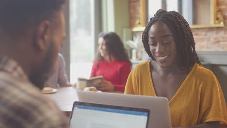 Pareja-De-Negocios-Con-Computadoras-Portátiles-Reuniéndose-Y-Trabajando-Juntos-En-Una-Cafetería