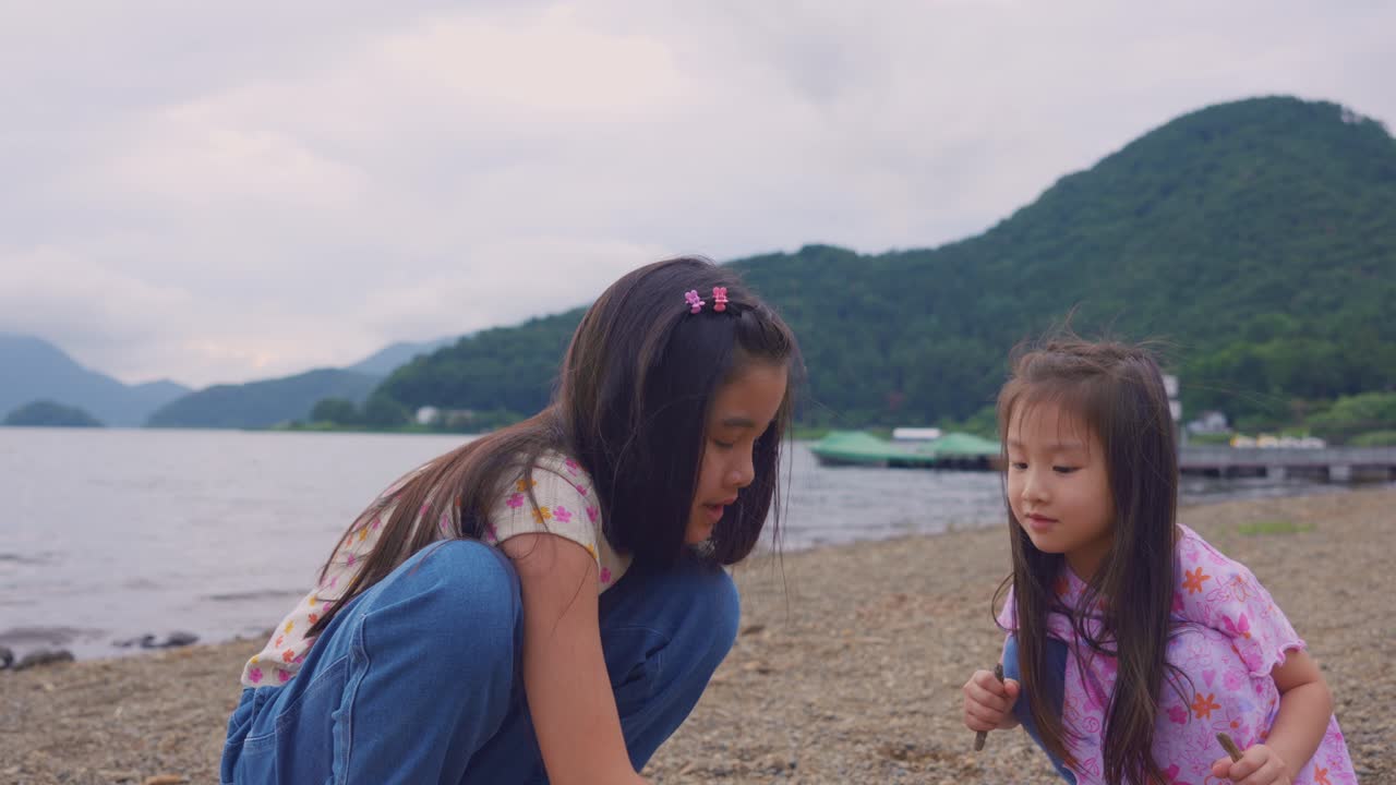 두 명의 어린 소녀들이 호수 해변에서 시간을 즐기고 있습니다.