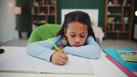 tired little girl studying at her desk