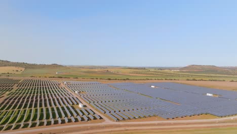 Wide-side-pan-over-large-solar-panel-field-on-sunny-day,-aerial