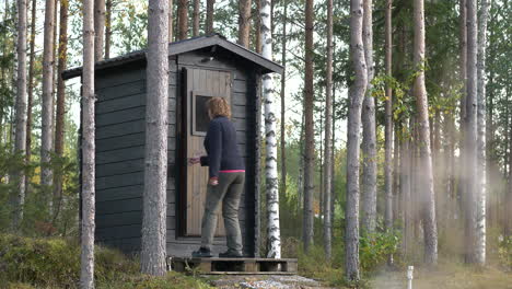 exterior of woman walking into outdoor toilet, rural scene