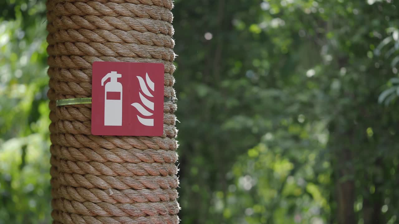 Fire Safety Sign on Rope-Wrapped Post in Green Environment
