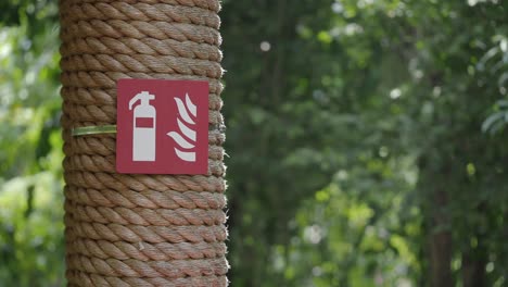 fire safety sign on rope-wrapped post in green environment