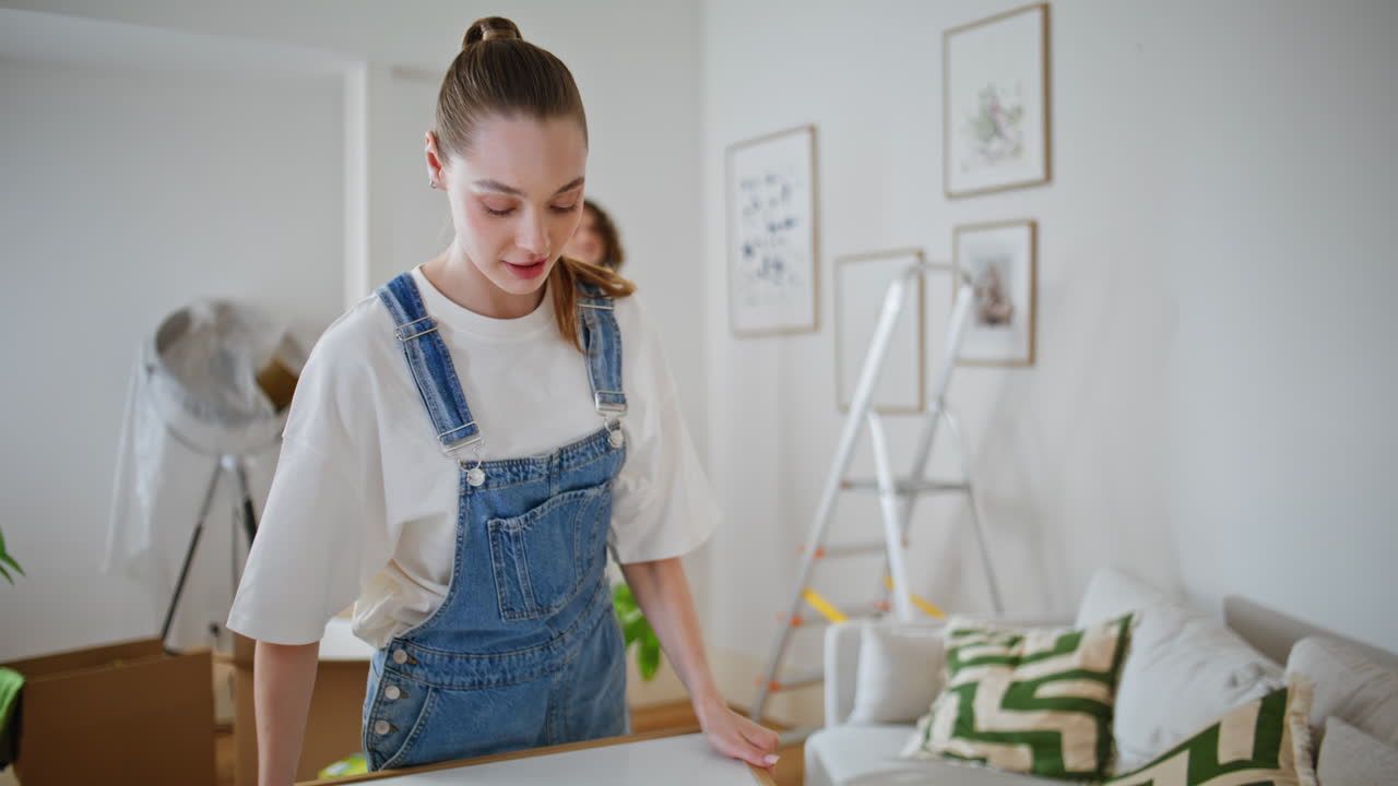 Felice coppia che sistema le decorazioni dell'appartamento in un soggiorno luminoso. Donna sorridente