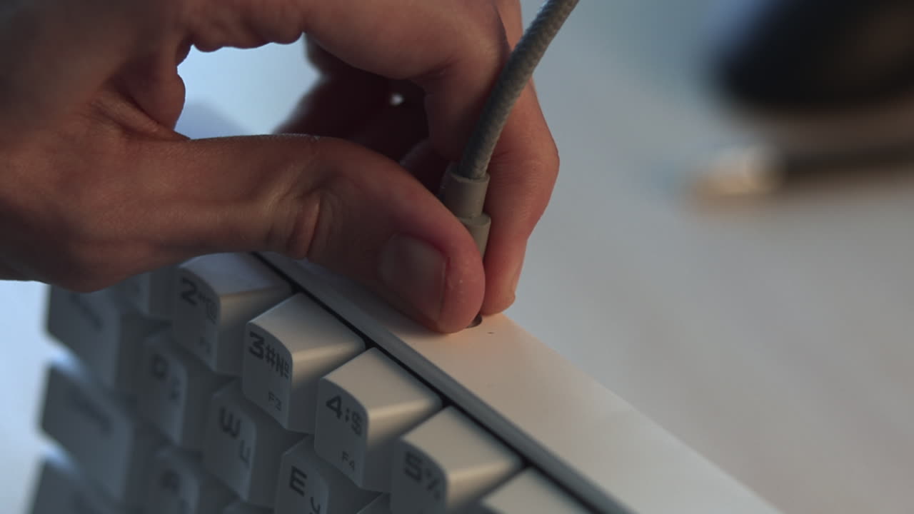 Indsætter stik i tastaturport, nærbillede af tekniker tester lydstik på hvidt mekanisk tastatur
