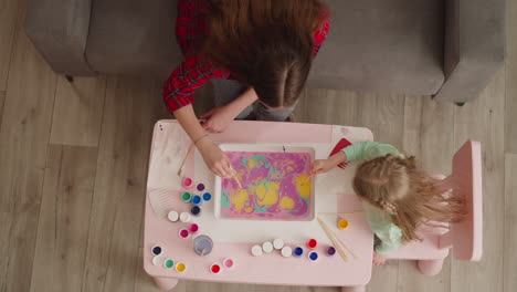 mother teaches little daughter to draw patterns at ebru art