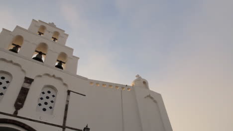 panning shot of a greek orthodox cycladic church with a greek flag flapping in front of it