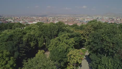 aerial view of konya city, drone descends from the city towards the trees of alaeddin hill