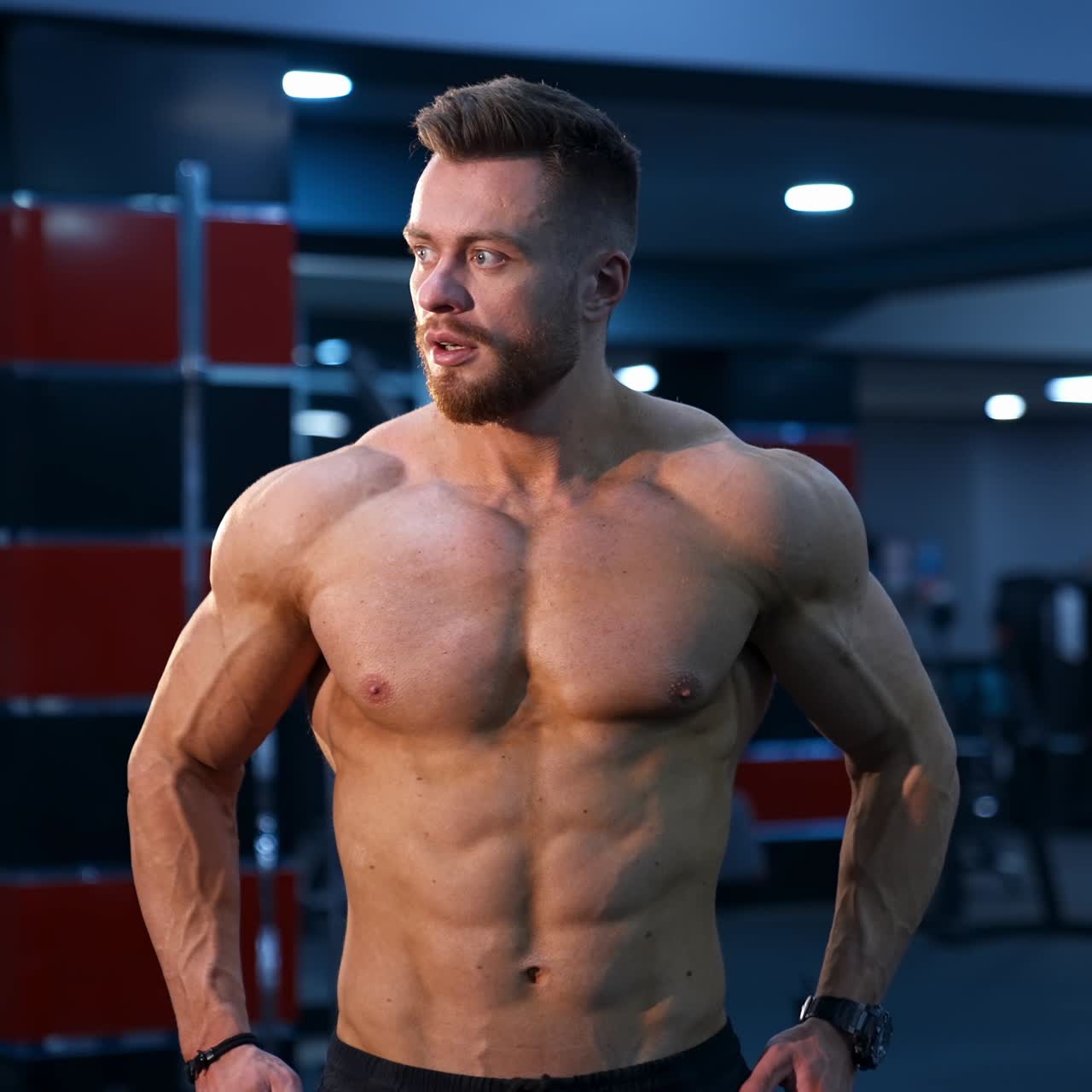 Strong young sportsman shows big muscles poses to the camera. Perfect body and strong abs. Slow motion