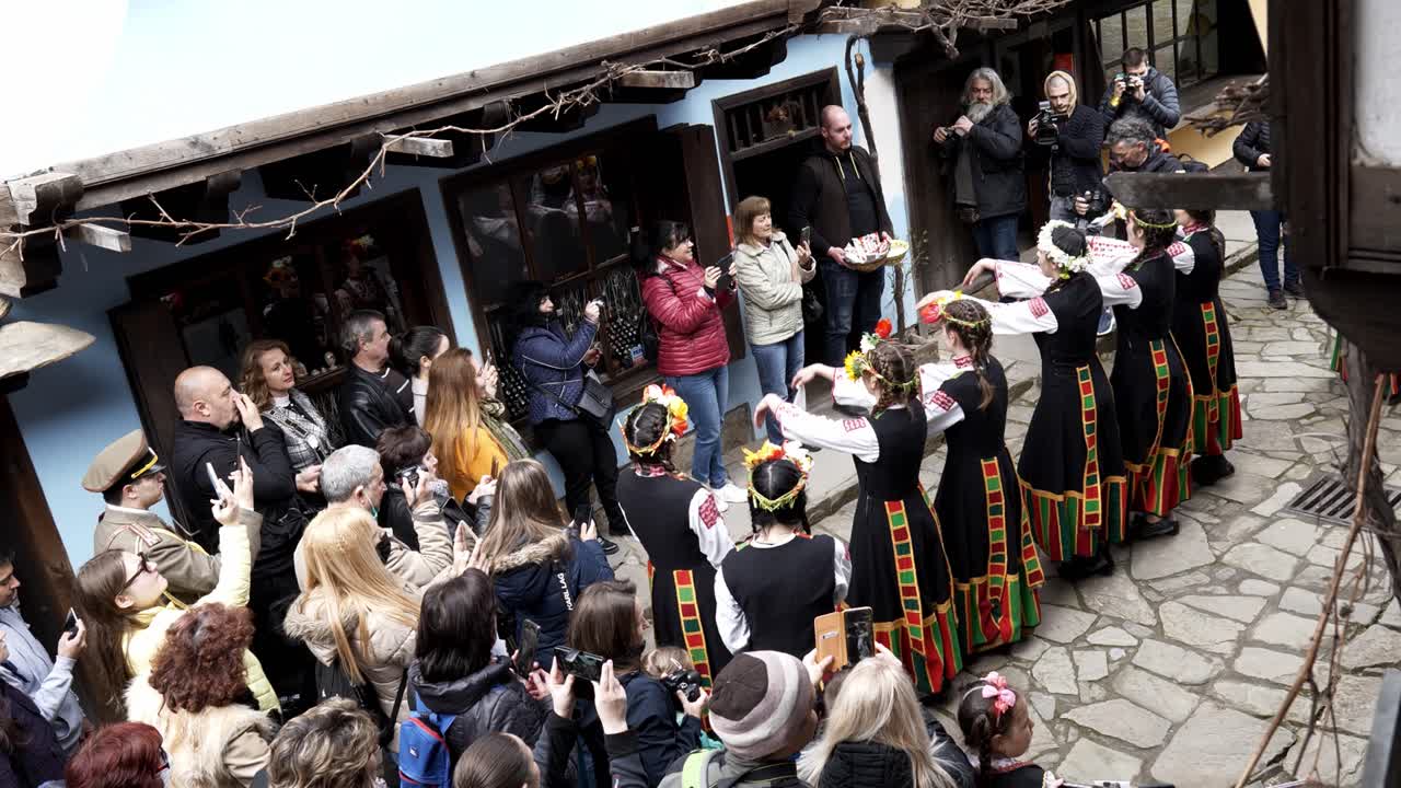 Pretty, Bulgarian girls in colourful traditional dress happily perform in front of crowds