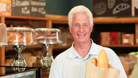 senior man with baguettes in supermarket