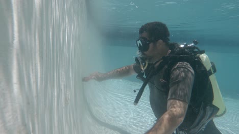 un limpiador profesional de piscinas con equipo de buceo limpia una piscina bajo el agua