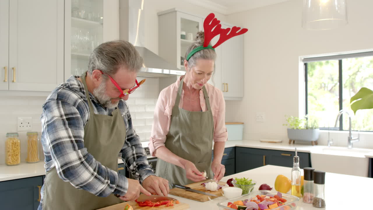 At Christmas, Festive couple preparing holiday meal together in kitchen, wearing reindeer antlers