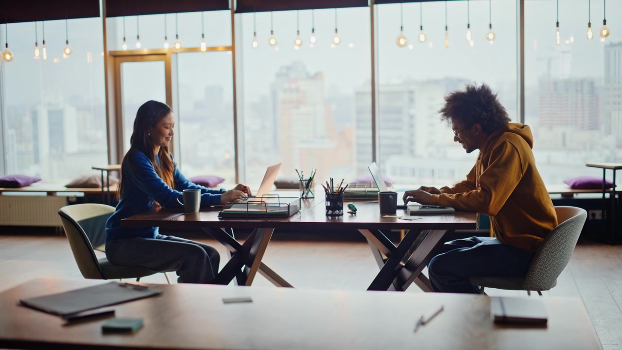 Two coworkers arriving coworking space. Diverse employees start work laptop.