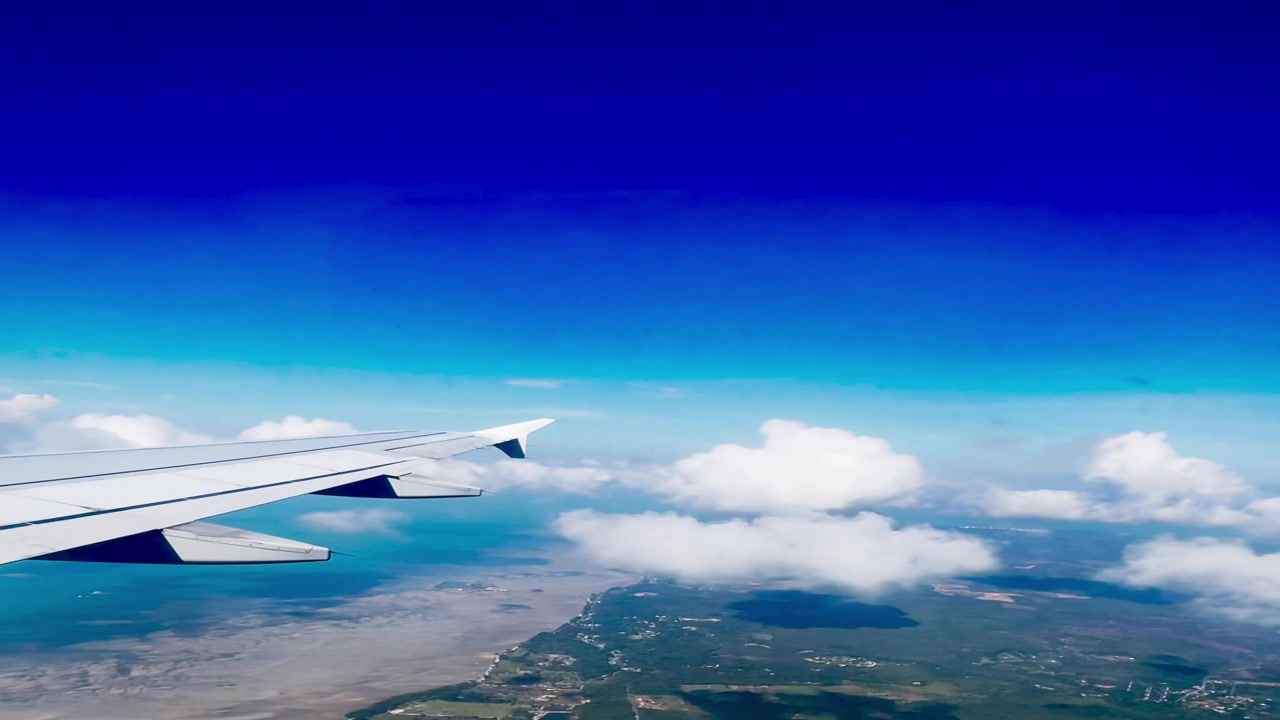 Vista aerea dell'ala di un aereo sopra la costa e le nuvole