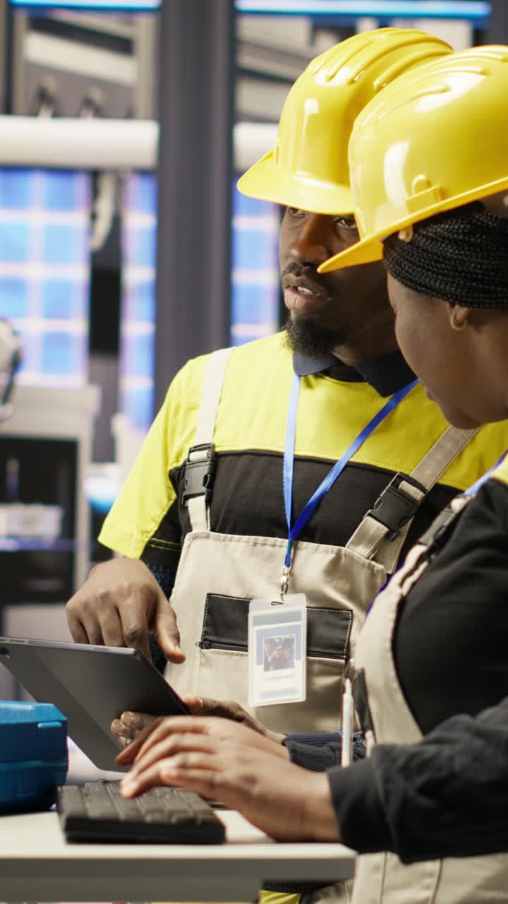 Vertical video Engineering team using PC in smart factory to oversee robotic assembly lines