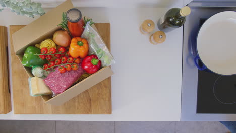 View-from-above-of-woman-with-recipe-cards-and-box-of-delivered-ingredients-planning-meal---shot-in-slow-motion