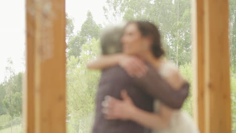 a touching clip shows a mother and her daughter, the girlfriend, giving each other a strong, loving hug near a large window with a beautiful natural landscape in the background.