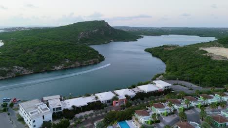 boat drives up winding channel into piscadera harbor curacao at dawn