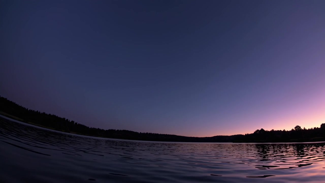 Superficie tranquila de lago reflejando un cielo crepuscular colorido