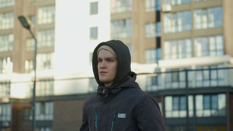 coach jogging on outdoor sport arena with focused expression, showcasing determination, fitness, perseverance, and dedication against a residential building backdrop and wire mesh