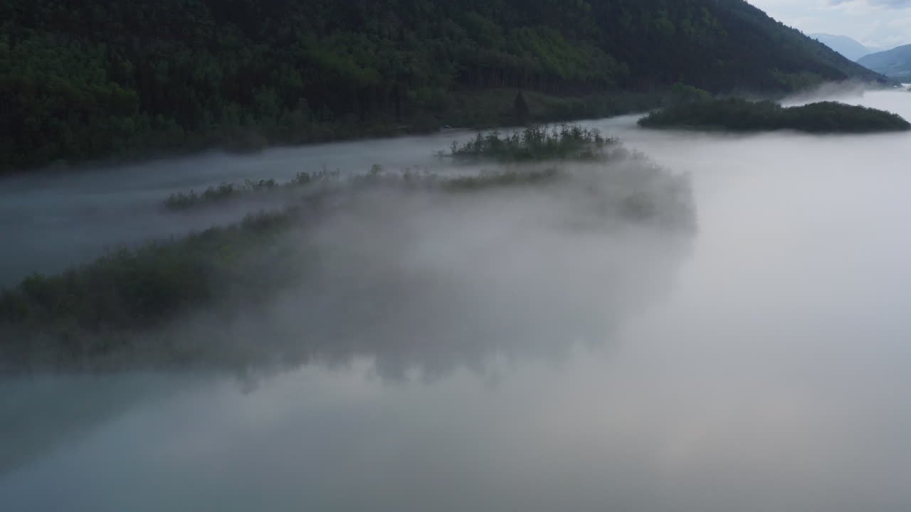 Flight over a foggy river. The mist is hanging low over the landscape creating a dark mystical mood over the whole scene.