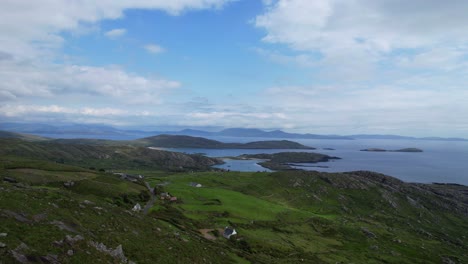 aerial view of remote rural houses nestled amidst lush green hills and coastline along the ring of kerry, ireland