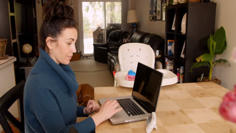 Mujer-Sentada-En-La-Mesa-De-La-Cocina-Usando-Una-Computadora-Portátil