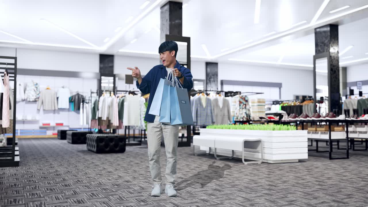 옷 가게 에 서 있는 동안 카메라 를 가리키고 미소 짓기 전 에 쇼핑 가방 을 들고 있는 아시아 의 쇼핑 남자 의 전체 모습