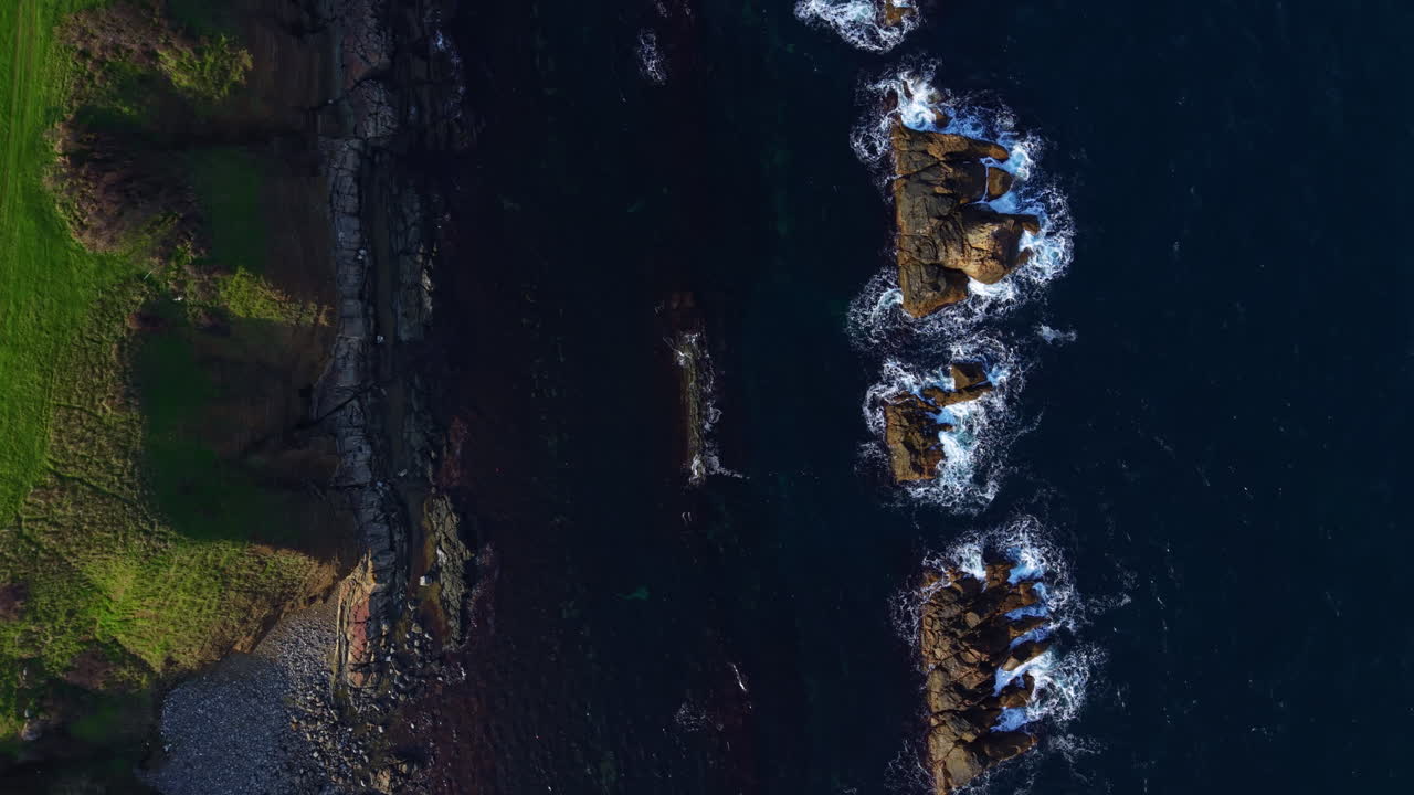 Fantastisk luftfoto av ulendt kystlinje under gyllent sollys med brusende bølger på steinformasjoner i skumringen