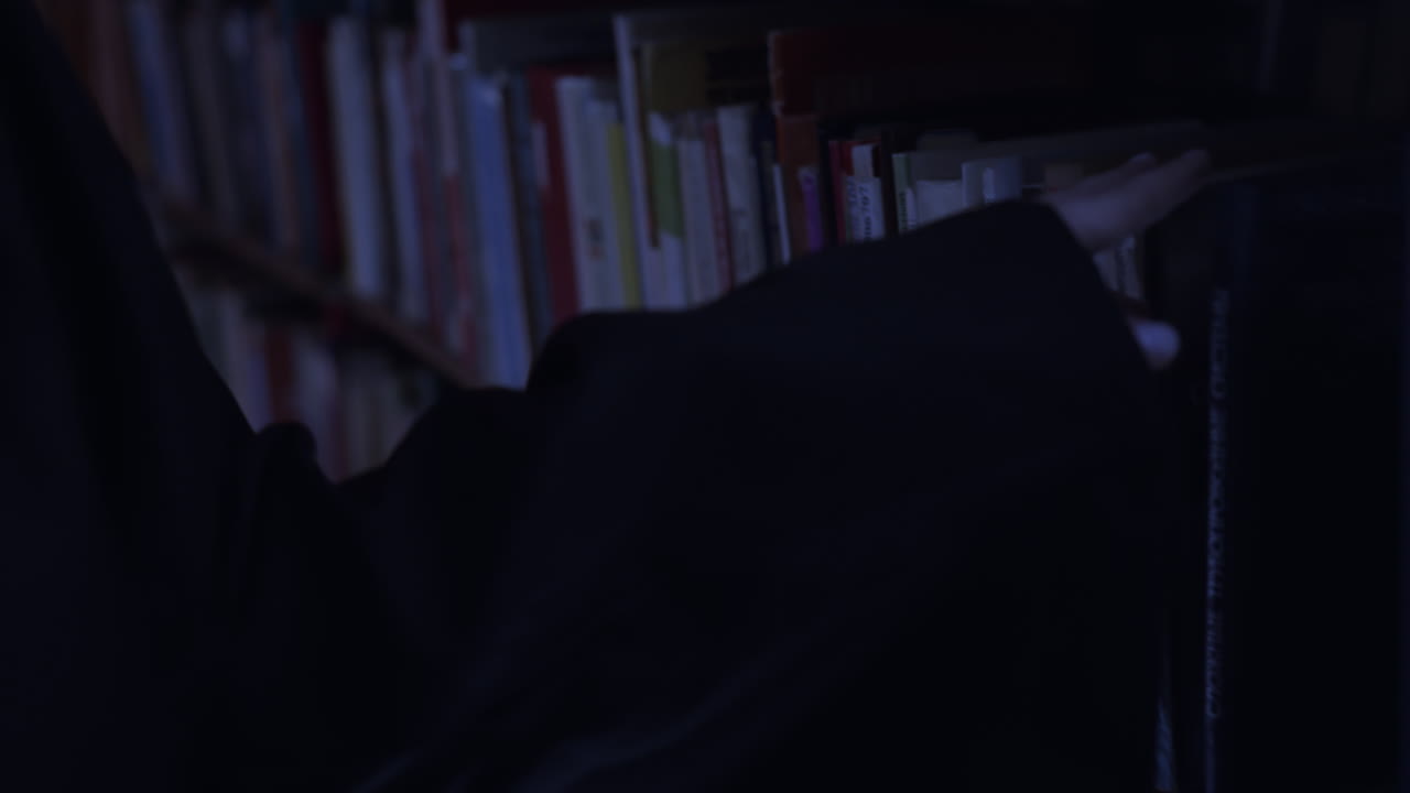 Person browsing through books in dark library