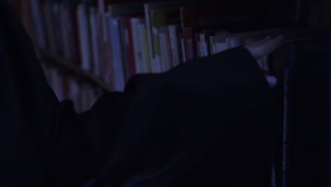person browsing through books in dark library