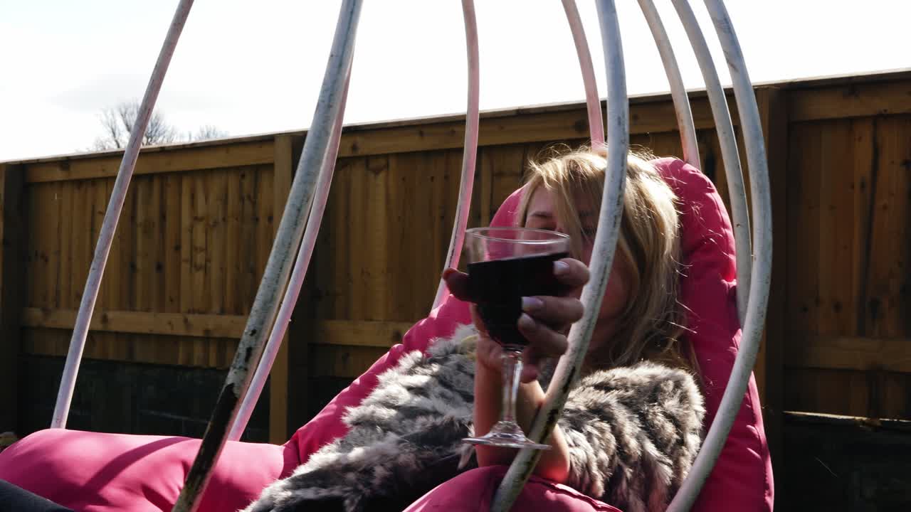 정원 의자 스 ⁇  4k 슬로우 모션에서 와인 한 잔과 함께 휴식을 취하는 매력적인 여성