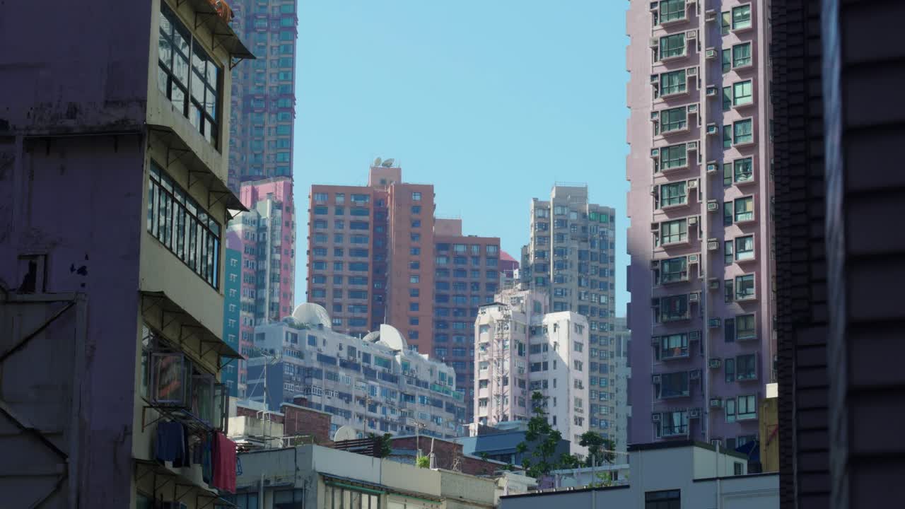 Vista panorâmica de edifícios de apartamentos e arranha-céus no centro de Hong Kong, China, em um dia ensolarado, mostrando a densidade da vida urbana e a arquitetura moderna.