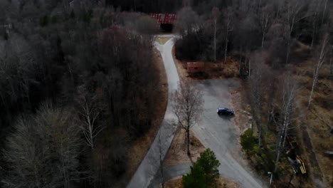 Toma-De-Drones-De-Un-Automóvil-Estacionado-Junto-A-Un-Camino-De-Grava-En-La-Naturaleza,-En-Suecia