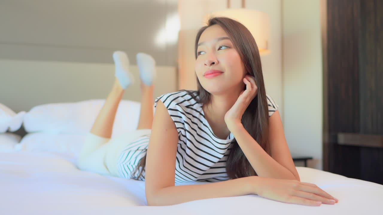 생각하고 웃는 침대에 누워 아름다운 백일몽 아시아 여자의 초상화