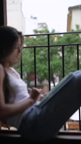 woman drawing on tablet at window in rainy weather